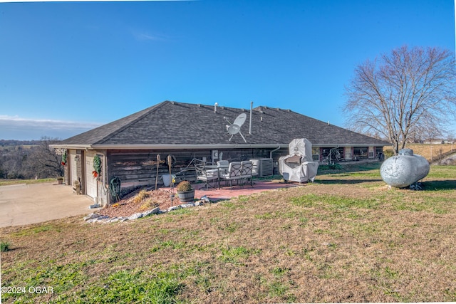 rear view of house with a patio area, a yard, and a garage