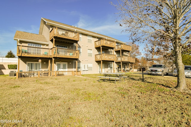 rear view of house featuring a lawn and central air condition unit