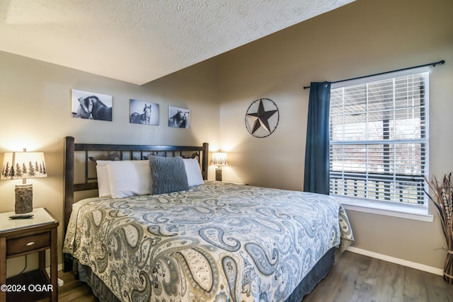 bedroom with dark wood-style floors, a textured ceiling, and baseboards