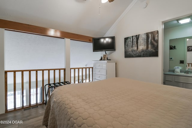 bedroom featuring visible vents, ensuite bathroom, vaulted ceiling, a sink, and wood finished floors