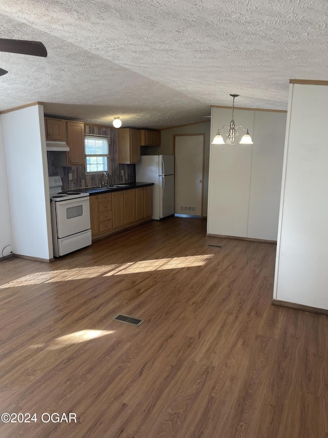 kitchen featuring white appliances, sink, pendant lighting, a chandelier, and dark hardwood / wood-style floors