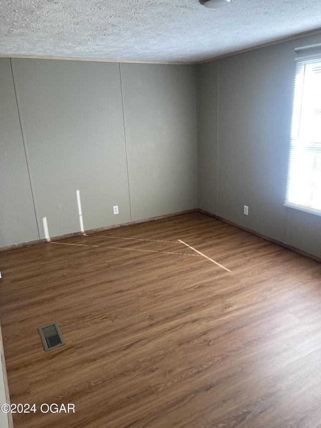 unfurnished room featuring wood-type flooring and a textured ceiling