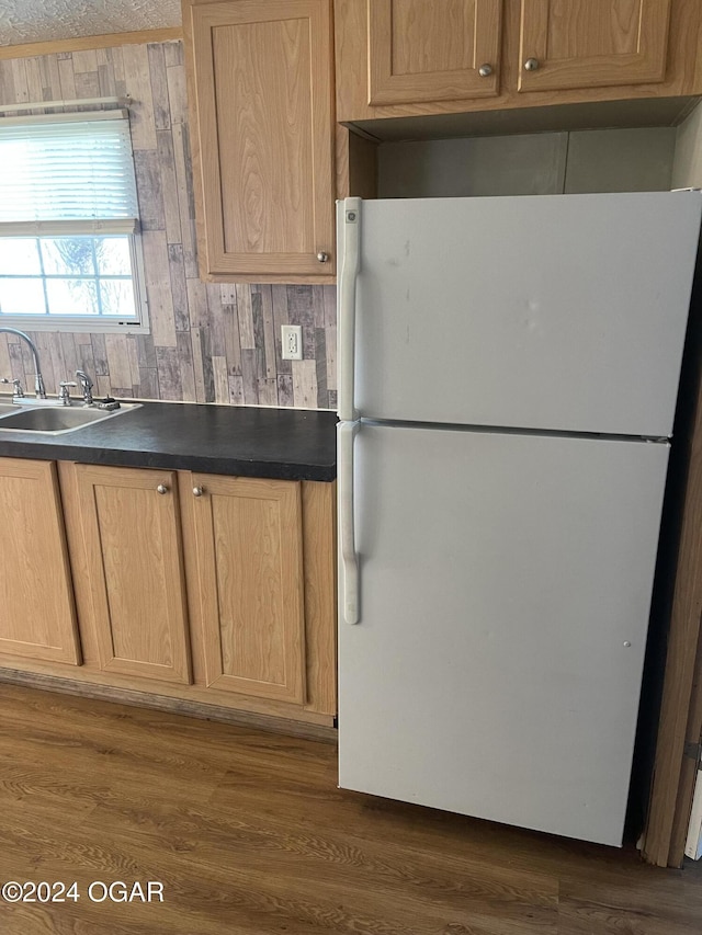 kitchen featuring dark hardwood / wood-style floors, white refrigerator, sink, and wooden walls