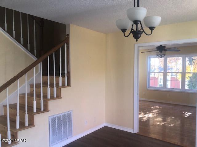 interior space featuring visible vents, a textured ceiling, baseboards, and wood finished floors