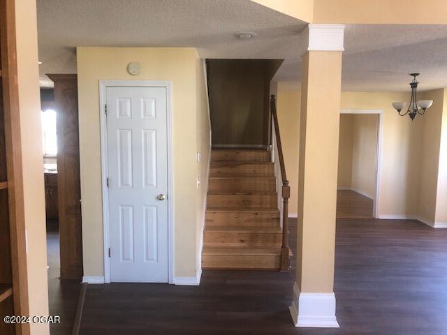 stairway with ornate columns, a textured ceiling, baseboards, and wood finished floors