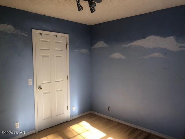 spare room with a textured ceiling, baseboards, and wood finished floors