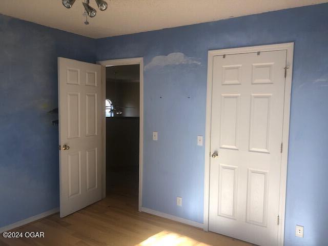 unfurnished bedroom with wood finished floors and baseboards