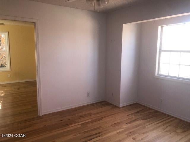 unfurnished room with ceiling fan, baseboards, and wood finished floors