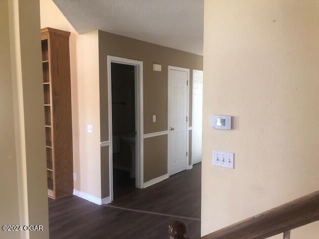 hallway with dark wood-style flooring and baseboards