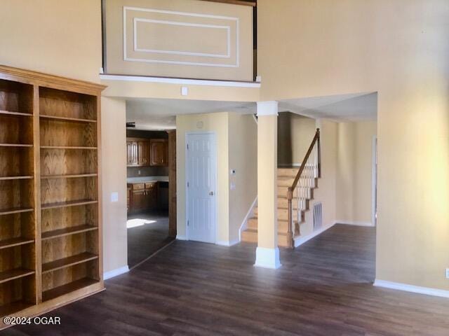 hall with dark wood finished floors, stairway, and a high ceiling