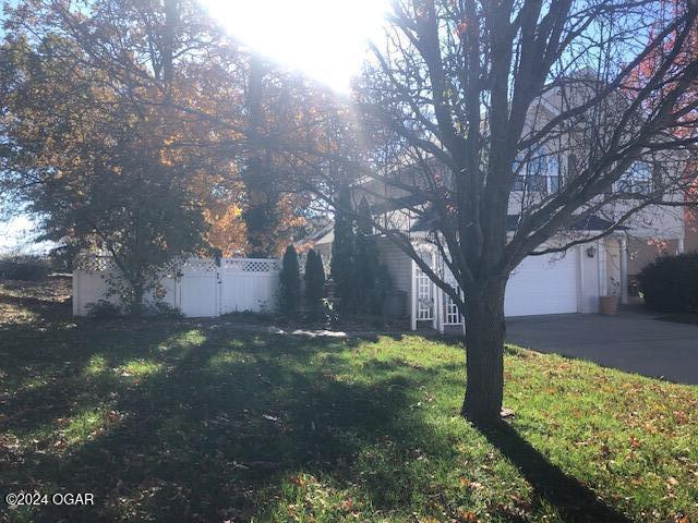 view of side of property with a garage, fence, and a yard