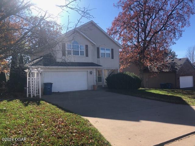 traditional-style house with a garage, aphalt driveway, and stucco siding