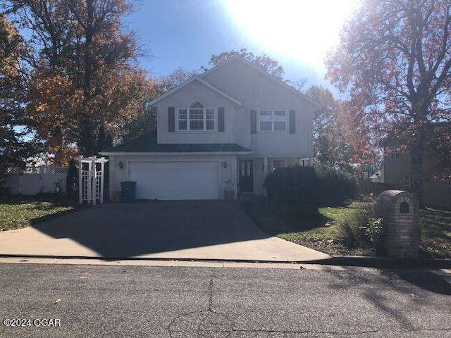 traditional-style home with an attached garage and aphalt driveway