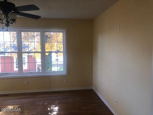 empty room featuring ceiling fan, baseboards, and wood finished floors