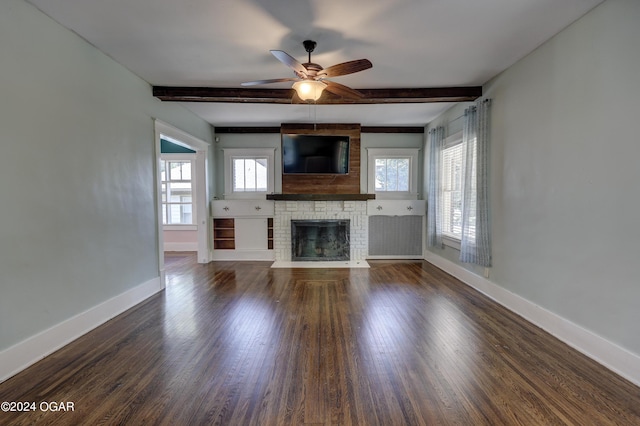 unfurnished living room with beamed ceiling, dark hardwood / wood-style flooring, a brick fireplace, and ceiling fan