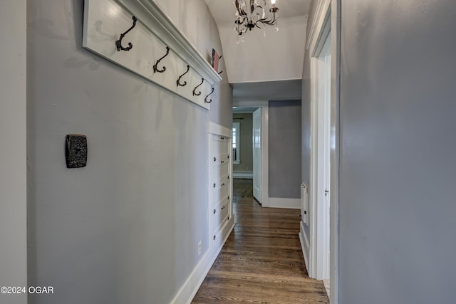 hallway with a baseboard radiator, dark hardwood / wood-style floors, and an inviting chandelier