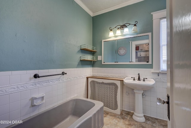 bathroom with tile patterned flooring, ornamental molding, a tub, and tile walls