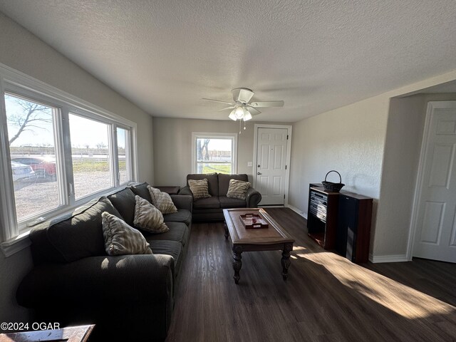 living room with a textured ceiling, dark hardwood / wood-style flooring, and ceiling fan