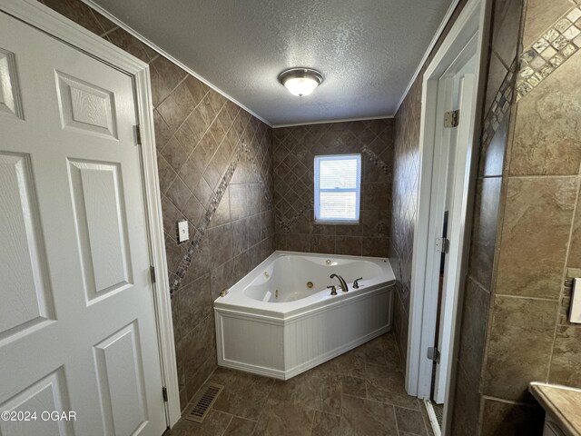 bathroom featuring tile patterned floors, tile walls, a bathtub, and a textured ceiling