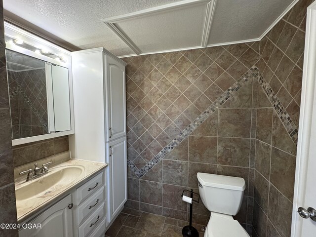 bathroom featuring vanity, a textured ceiling, and tile walls