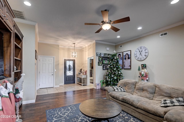 living room featuring ceiling fan with notable chandelier, light wood-type flooring, and crown molding