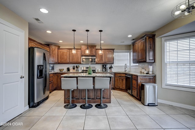 kitchen with sink, a center island, decorative light fixtures, a breakfast bar area, and appliances with stainless steel finishes