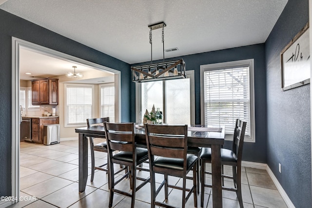 tiled dining room with a textured ceiling, a wealth of natural light, and a notable chandelier