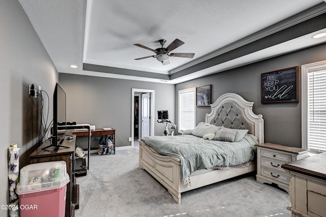 bedroom featuring a tray ceiling, ceiling fan, light colored carpet, and a textured ceiling