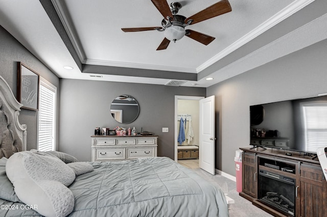 carpeted bedroom featuring a tray ceiling, multiple windows, and ceiling fan