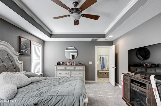 bedroom with connected bathroom, a raised ceiling, ceiling fan, and ornamental molding