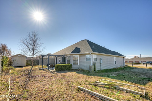 back of house featuring a yard, a pergola, and a shed