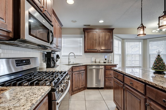 kitchen featuring tasteful backsplash, sink, stainless steel appliances, and decorative light fixtures