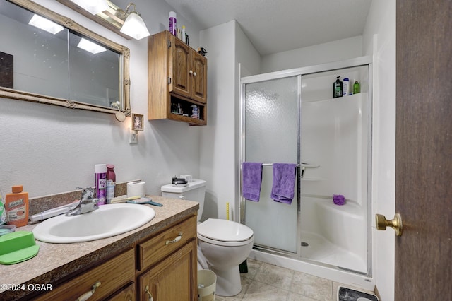 bathroom with tile patterned floors, a shower with door, vanity, and toilet