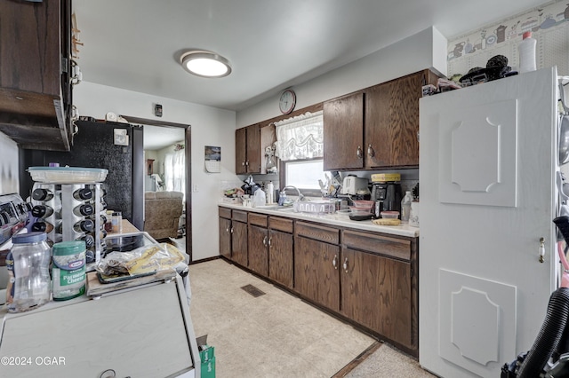 kitchen with dark brown cabinets, black fridge, and sink