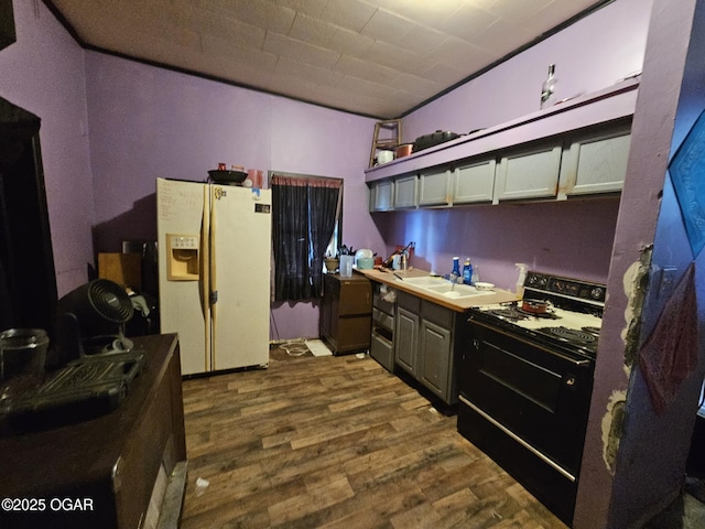 kitchen with white refrigerator with ice dispenser, sink, dark hardwood / wood-style flooring, and black / electric stove