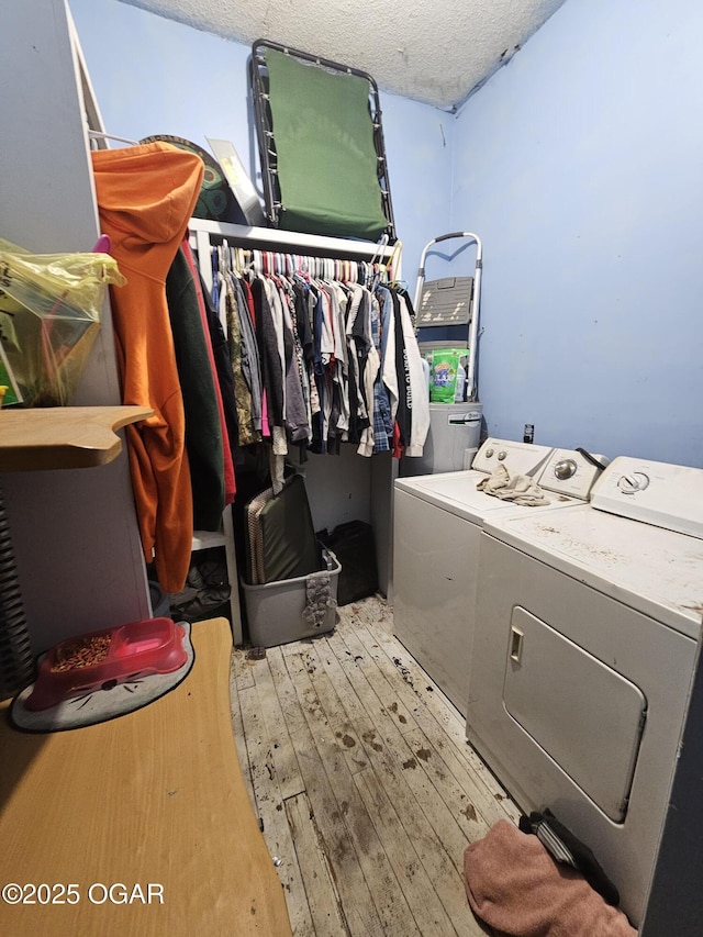 washroom with washer and dryer, a textured ceiling, and light wood-type flooring