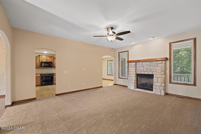 unfurnished living room with ceiling fan, a fireplace, and light colored carpet