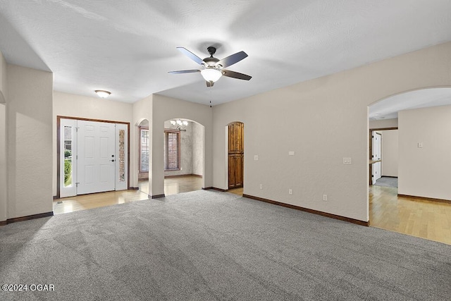 unfurnished living room with ceiling fan, light colored carpet, and a textured ceiling