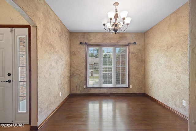 unfurnished dining area with dark hardwood / wood-style floors and an inviting chandelier