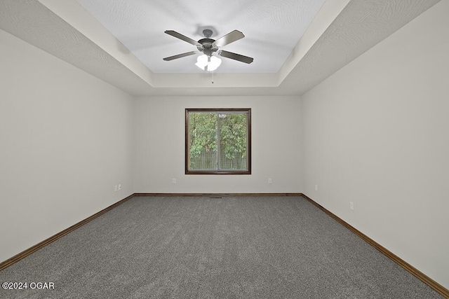 carpeted empty room featuring ceiling fan, a textured ceiling, and a tray ceiling