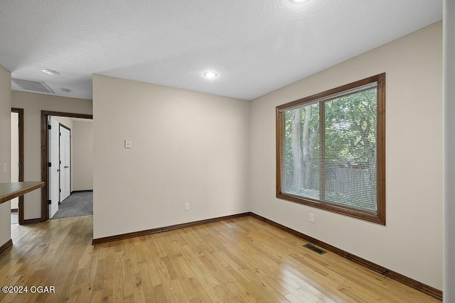 spare room featuring light hardwood / wood-style floors and a textured ceiling