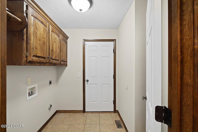 laundry area with cabinets, washer hookup, electric dryer hookup, a textured ceiling, and light tile patterned floors