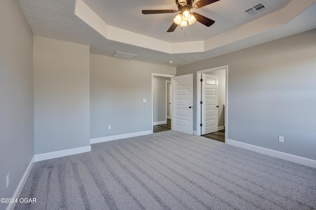 carpeted spare room featuring a tray ceiling and ceiling fan