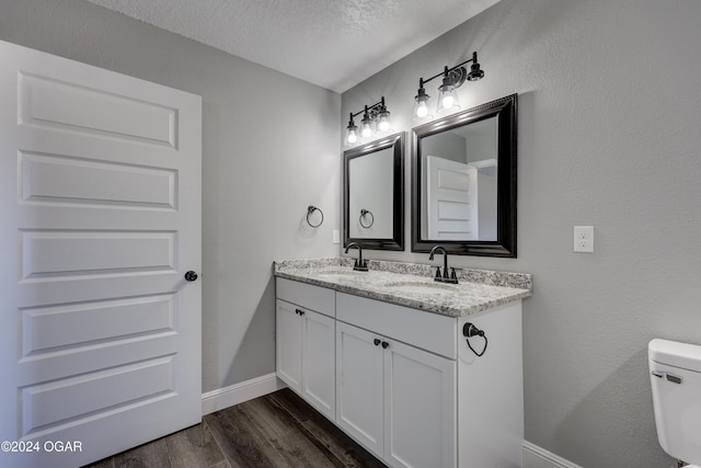 bathroom featuring vanity, hardwood / wood-style floors, a textured ceiling, and toilet