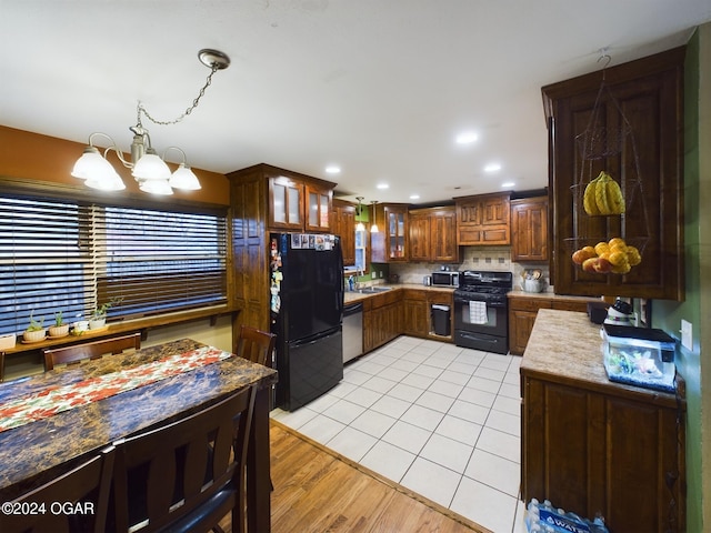 kitchen with backsplash, black appliances, sink, light hardwood / wood-style flooring, and a chandelier