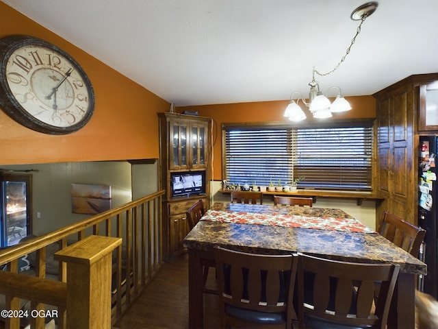 dining room with dark wood-type flooring, lofted ceiling, and a notable chandelier