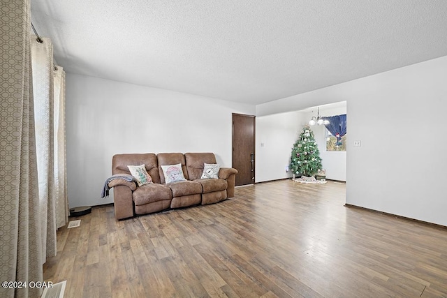 living room with a chandelier, hardwood / wood-style floors, and a textured ceiling