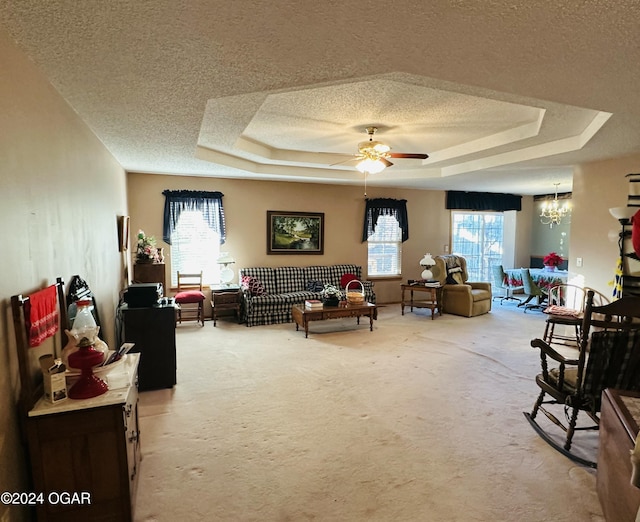 interior space featuring a raised ceiling, plenty of natural light, a textured ceiling, and ceiling fan with notable chandelier