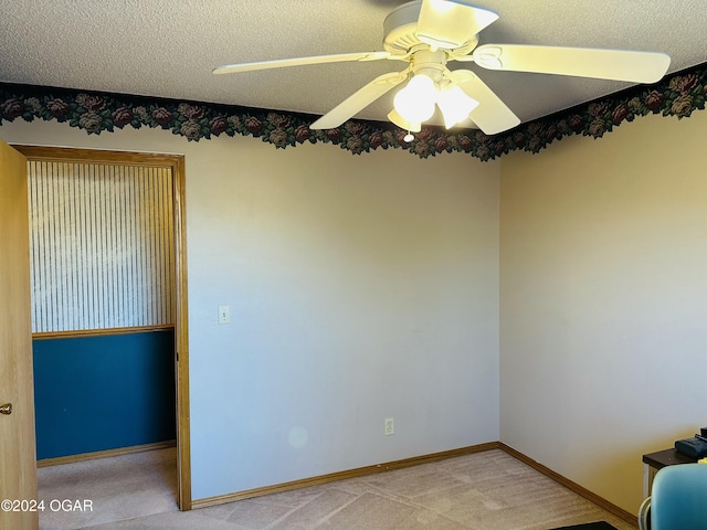 carpeted spare room featuring ceiling fan and a textured ceiling