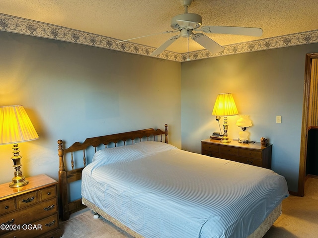 bedroom with ceiling fan, carpet floors, and a textured ceiling